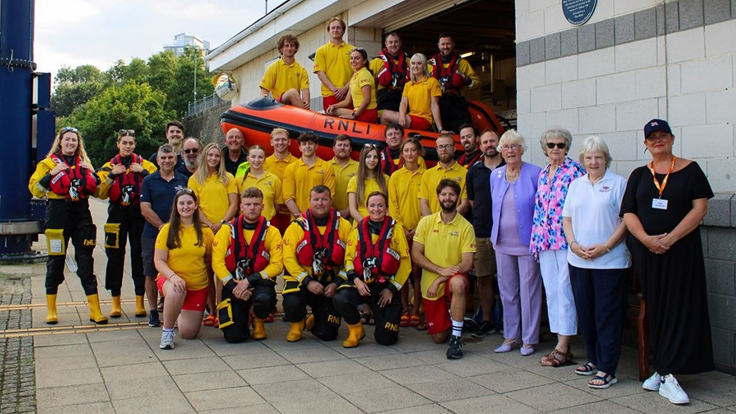 RNLI crewmembers stood around an inshore lifeboat. 