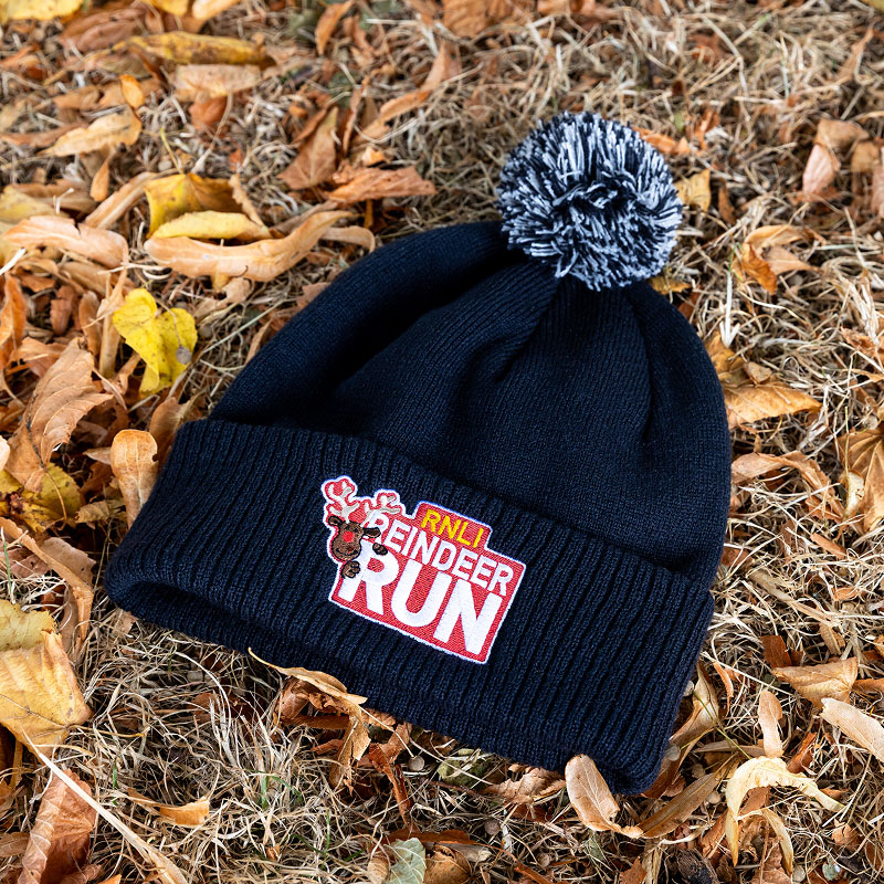 RNLI Reindeer Run beanie, photographed on fallen autumn leaves.