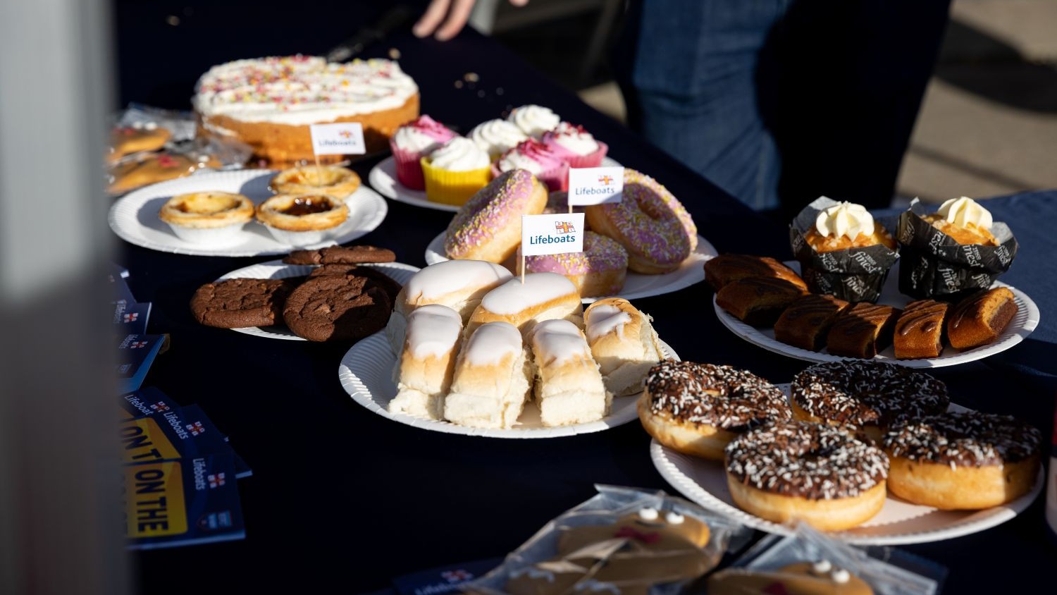 A selection of cakes with lifeboat flags laid out on a table