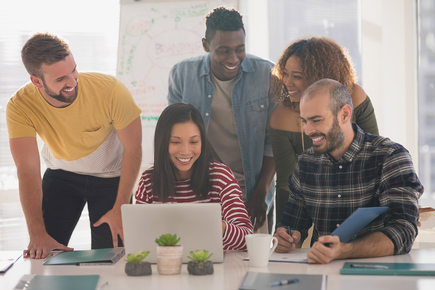A group stood looking at a laptop