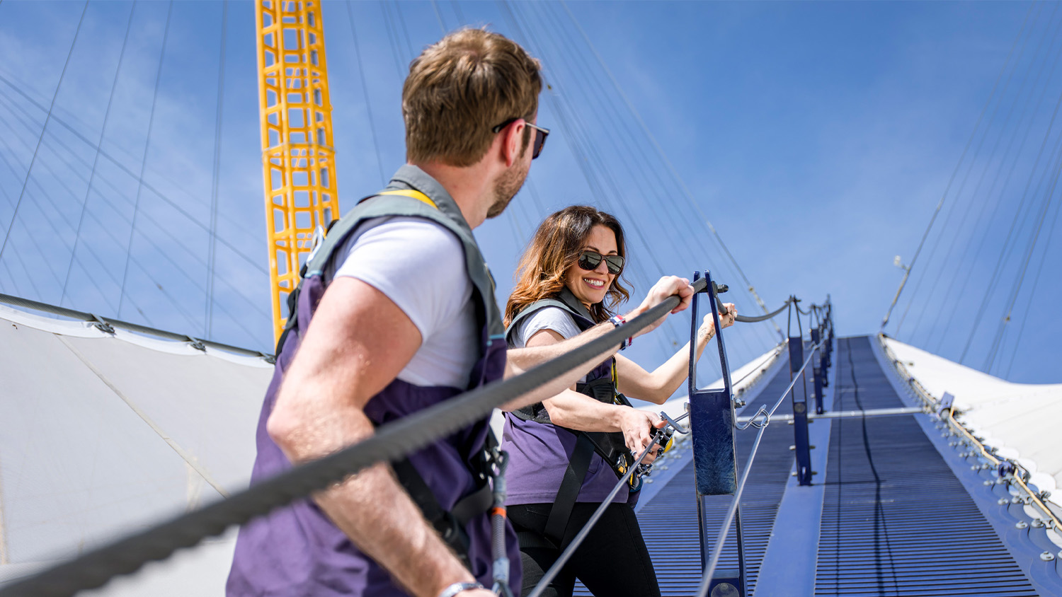 Two people happily climbing the O2 arena together